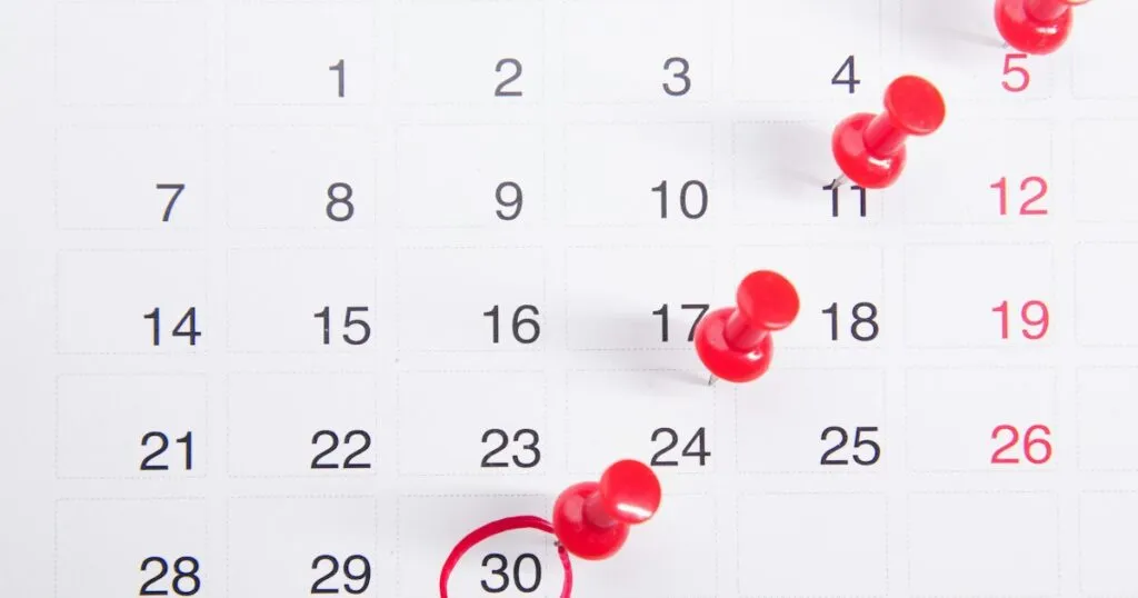 Calendario mensual con varias fechas marcadas con chinchetas rojas