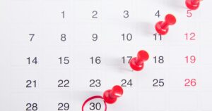 Calendario mensual con varias fechas marcadas con chinchetas rojas
