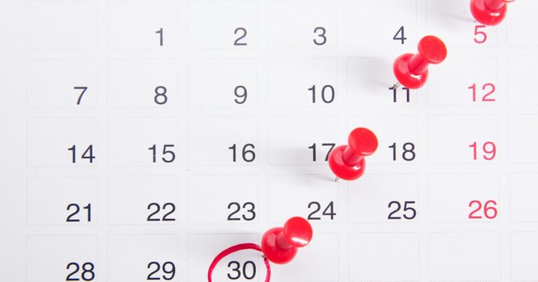 Calendario mensual con varias fechas marcadas con chinchetas rojas