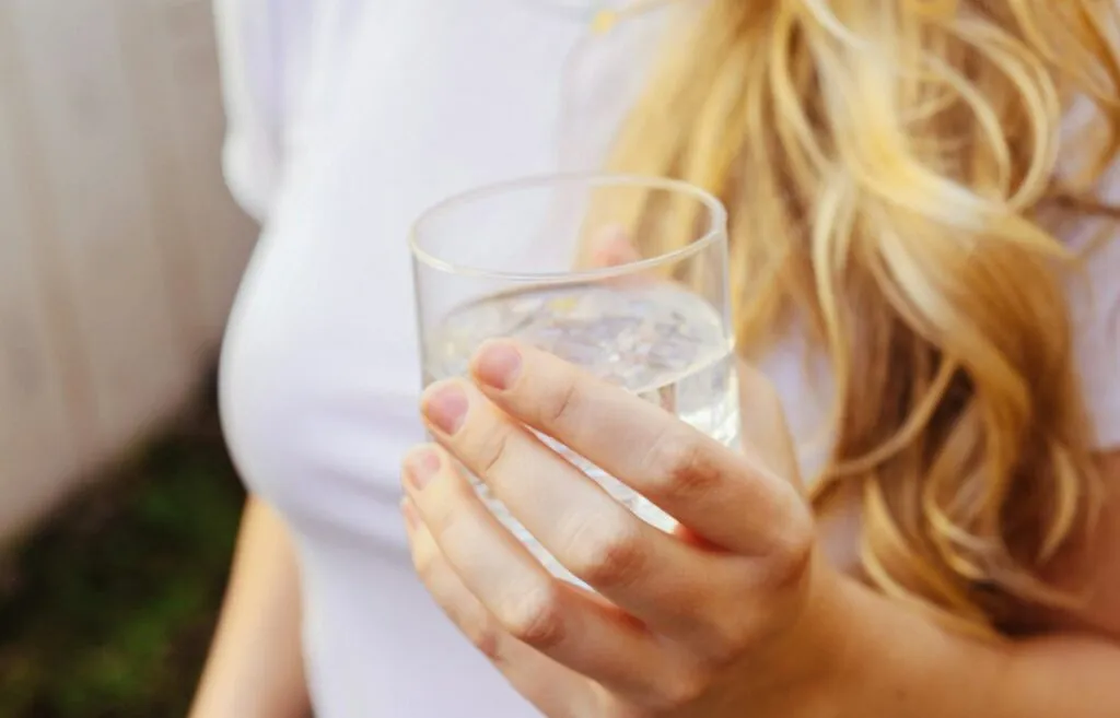Mujer sostiene un vaso de agua en la mano