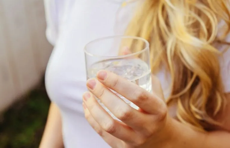 Mujer sostiene un vaso de agua en la mano