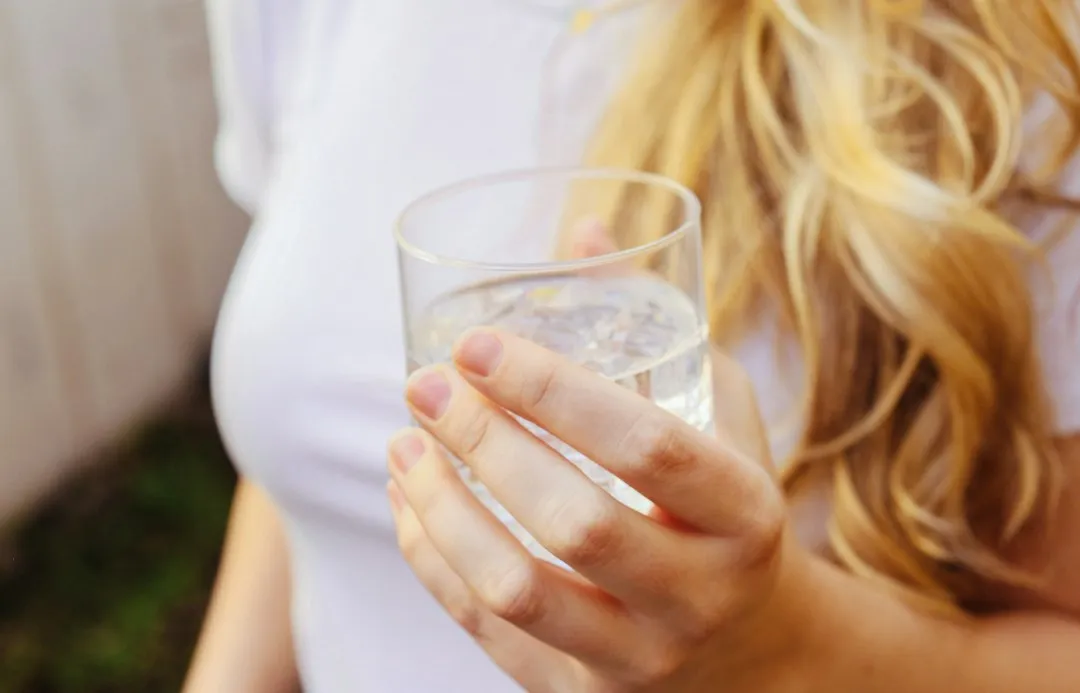 Mujer sostiene un vaso de agua en la mano