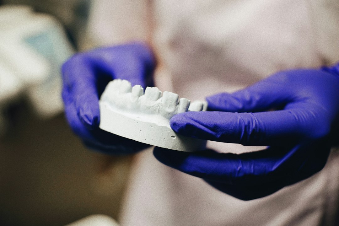 Gloved hands holding a plaster dental model