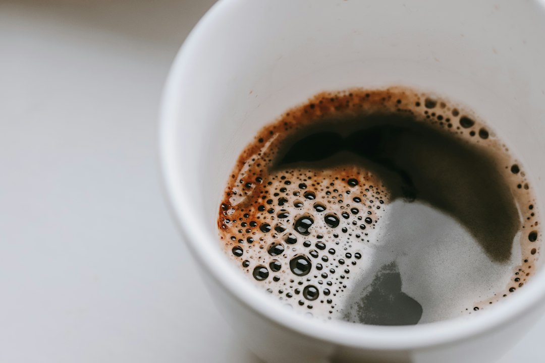 Cup of black coffee seen from above on a light surface