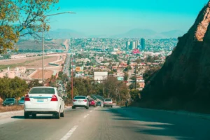 Vista panorámica de Tijuana desde una avenida en pendiente, con tránsito y edificios de la ciudad.