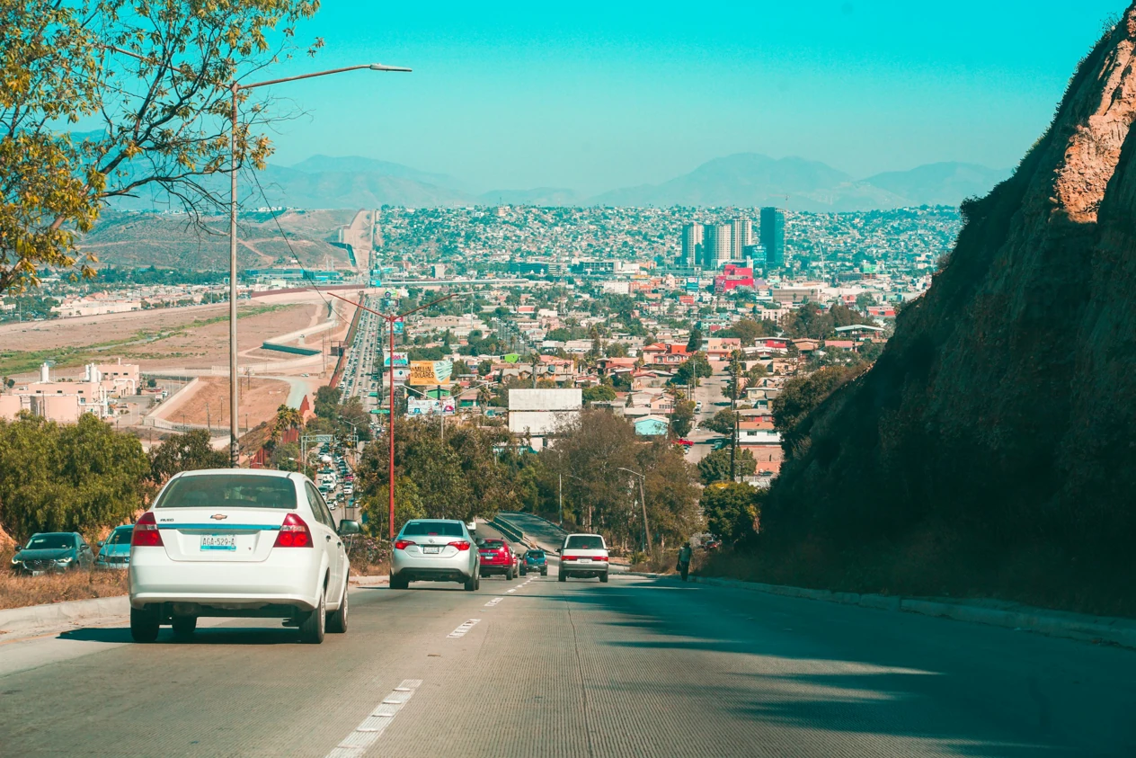 Panoramic view of Tijuana from a descending avenue, with traffic and city buildings.